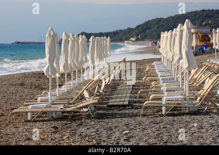 Filas de sillas de playa y sombrillas vacías en una playa organizada Foto de stock