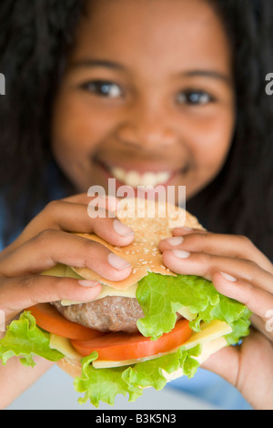 Muchacha comiendo hamburguesa sonriente Foto de stock