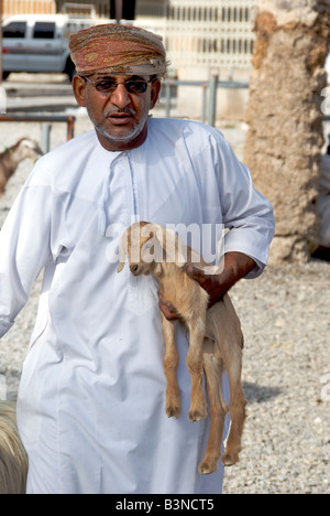 El hombre lleva bebé ganado caprino souq o mercado región Dakhiliyah Nizwa al Sultanato de Omán Foto de stock