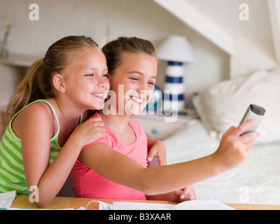 Las niñas distraen de sus tareas escolares, jugando con un teléfono móvil