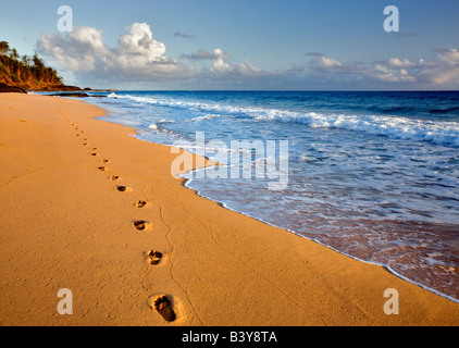 Amanecer en Playa del Secreto con huellas en la arena en Kauai Hawaii Foto de stock