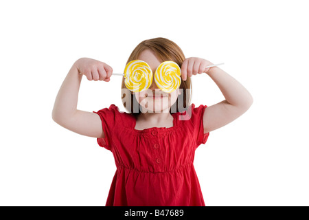 Una niña que cubre sus ojos con lollipops Foto de stock