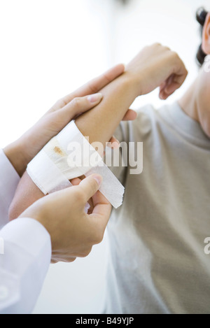 Doctor aplicando una gasa al niño del brazo, vista recortada Foto de stock