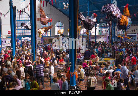 Multitudes de personas vagan sentarse y buscar puestos en el mercado Hall en Abergavenny Festival de Comida Foto de stock