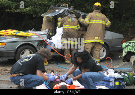 Los médicos trabajan mujer herida en un accidente de auto mientras los bomberos quitar el techo de un coche para llegar a una víctima atrapada en el coche Foto de stock