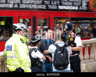 Oficiales de policía con detenido sospechoso y reportero en Oxford Circus London UK Foto de stock