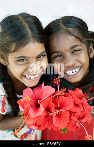 Dos muchachas indias sosteniendo flores hibiscus rojo. En Andhra Pradesh, India Foto de stock