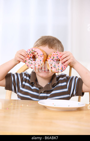 Joven celebración donuts sobre los ojos Foto de stock