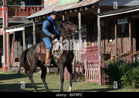 Un vaquero cabalga en un pueblo del viejo oeste Foto de stock