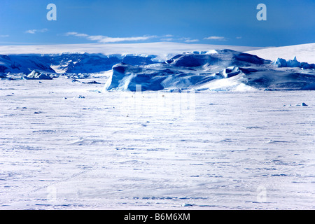 Cuatro personas diminutas distante senderismo en fast hielo cubierto de nieve y glaciares lejanos hacia el témpano de hielo cerca de la isla Snow Hill fuera de la Península Antártica. Foto de stock