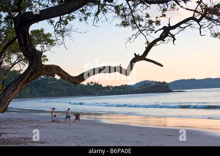 La gente disfruta de la playa al atardecer a lo largo de Playa Flamingo en Costa Rica Foto de stock