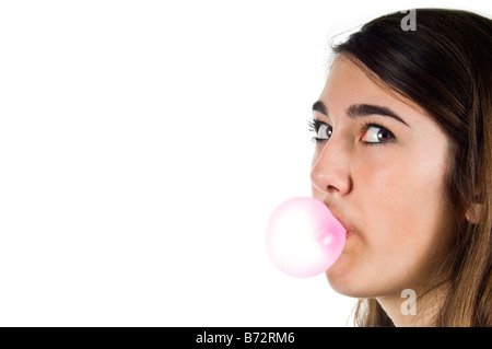 Cierre horizontal retrato de un joven adolescente soplando una burbuja con big pink bubblegum contra un fondo blanco. Foto de stock