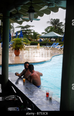 Dos turistas sentarse en el bar de la piscina durante una tormenta de lluvia en un complejo vacacional del caribe Foto de stock