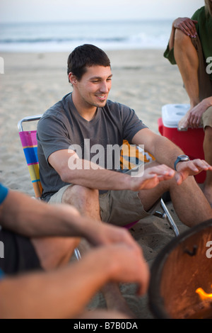 Grupo de Amigos sentados alrededor de una fogata en la playa, en Santa Cruz, California, Estados Unidos. Foto de stock