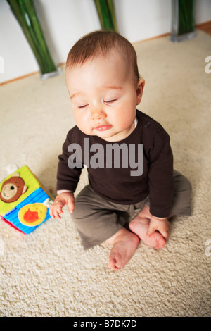 Bebé de 4 meses de edad sentado con los pies descalzos sobre una alfombra.  Juguetes en primer plano Fotografía de stock - Alamy