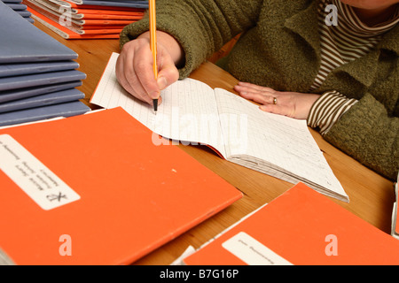 Maestro de escuela primaria marcando los alumnos deberes libros de estudio en casa por la tarde Foto de stock