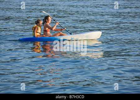 Madre e hija de remo de kayak en el lago