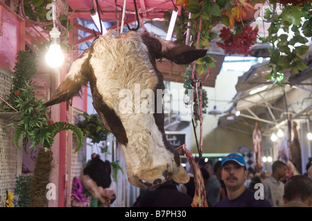 Una vaca decapitada cabeza pende de un carnicero calar en un mercado de Meknes, Marruecos. Foto de stock