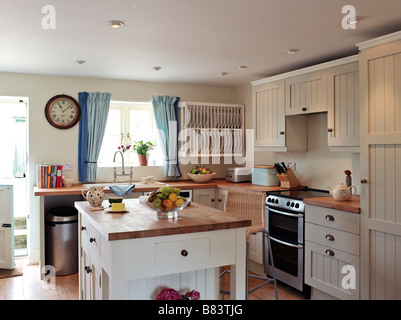 Cocina de estilo shaker con panel blanco alacenas y unidad central de isla de madera con superficies de trabajo Foto de stock