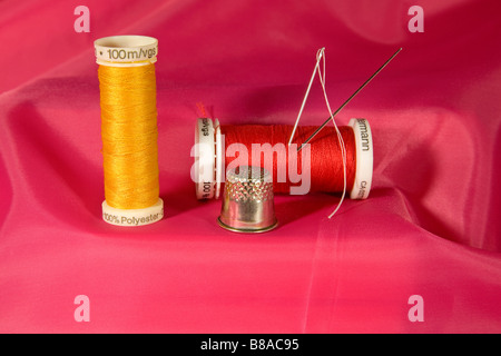 Un pequeño kit de costura con agujas bobinas de hilo y un dedal Foto de stock