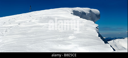 Alta montaña invernal con voladizo hada de la nieve tapa y huella humana sobre montañas nevadas seguimiento a trípode fotográfico Foto de stock