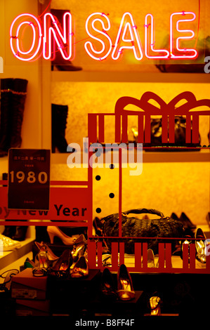A la venta el cartel de neón rojo en la ventana de una tienda con bolsos y zapatos, muestra en la tienda