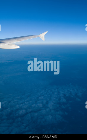 Ala de avión con el cielo azul, las nubes y el horizonte Foto de stock