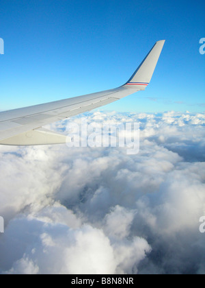 Ala de avión con el cielo azul y por encima de las nubes Foto de stock
