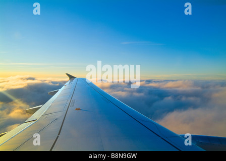 Ala de avión con el cielo azul y por encima de las nubes Foto de stock