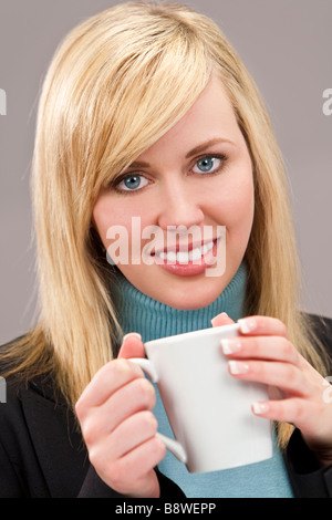 Una joven y bella mujer rubia bien vestido y beber una taza de té o café.