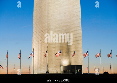 La base del Monumento a Washington con banderas estadounidenses y los visitantes al atardecer. Washington DC, Estados Unidos.