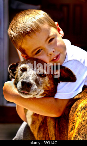 Un niño de cinco años abraza a su mongrel perro afuera en Laguna Niguel California Foto de stock