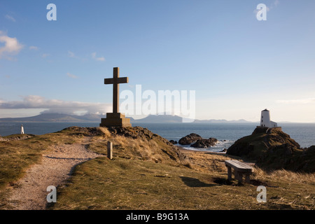 Cruz de piedra Memorial y el antiguo faro Twr Mawr en punto de Ynys Llanddwyn Isla AONB en la isla de Anglesey al norte de Gales, Reino Unido