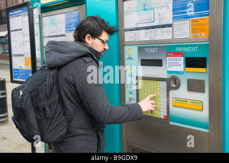 Hombre de comprar un billete en la máquina de billetes de tranvía Manchester UK Foto de stock