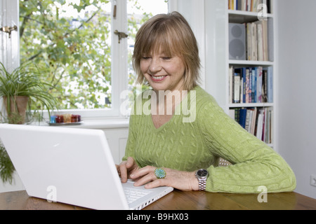 Entrada de datos portátil Senior detalle alegremente series personas mayores mujer ríe los equipos de trabajo de concentración de internet de interés Foto de stock