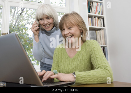 Los ancianos se ríe de entrada de datos portátiles teléfonos celulares detalle series personas mayores a las mujeres dos equipos alegremente los datos Foto de stock