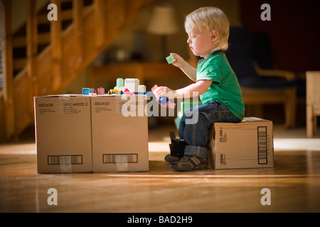 Niño jugando con juguetes en cajas de cartón