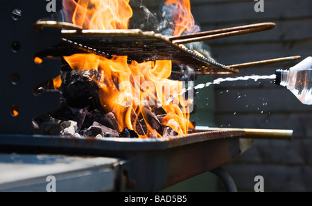 Squirting iluminación en un combustible líquido charcoal Bar-B-Q para aumentar las llamas.