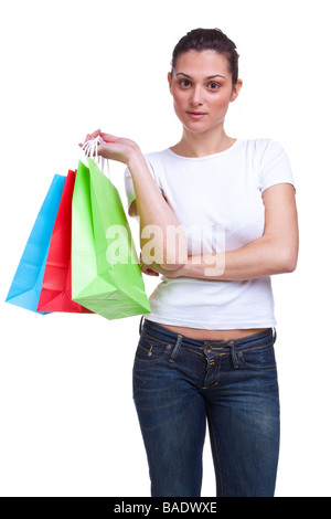 Una atractiva mujer joven espera brazos cruzados con coloridas bolsas de compras aisladas sobre fondo blanco Foto de stock