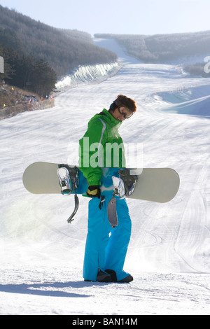 Snowboarder posando delante de un paisaje nevado Foto de stock