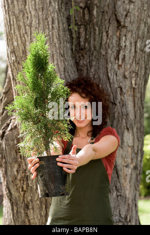 La mujer está junto al gran árbol, sujetando el árbol más pequeño hacia la cámara, Winnipeg, Manitoba, Canadá