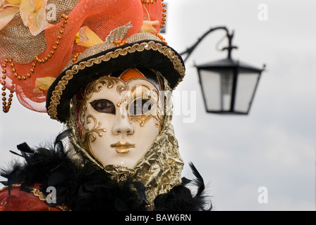 Disfraz de carnaval veneciano con una máscara de negro y plata penachos  negros y guantes cerca de una lámpara de la calle en San Marcos Fotografía  de stock - Alamy