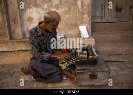 Un hombre se sienta en la calle trabajando en un typrewriter en el corazón del casco antiguo de la ciudad de Ahmedabad, Gujarat. Foto de stock