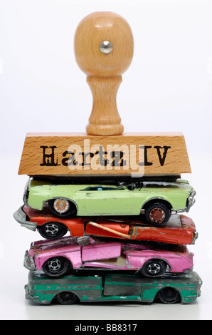 Hartz IV escrito en un sello, sobre trozos de coches en miniatura, la imagen simbólica para la prima de desguace para Hartz-IV beneficiarios