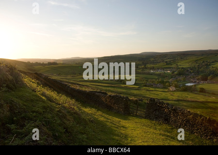 Puesta de sol, y una pared drystone enmarca la vista hacia la aldea de Burnsall, en Wharfedale, Yorkshire Dales, desde Burnsall cayó Foto de stock