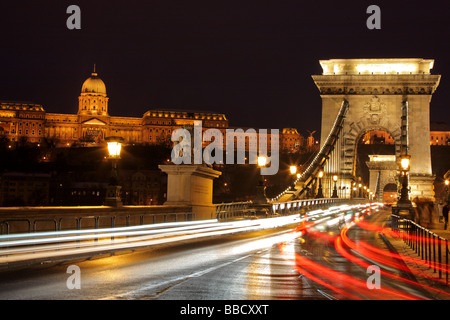 El tráfico en el puente de las cadenas y el Palacio Real de Buda en Budapest, Hungría por noche Foto de stock