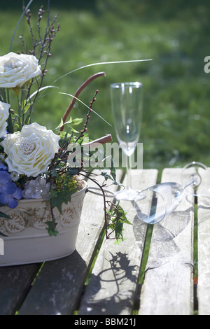 Flores y copas de champaña en la mesa de madera en el jardín Foto de stock