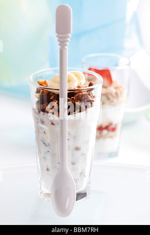 Chocolate muesli con yogur en un pequeño frasco de vidrio, rodajas de plátano, yogur y muesli de cuchara fresa