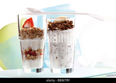Muesli y chocolate muesli con yogur y en un pequeño frasco de vidrio, rodajas de plátano, fresas, yogurt cuchara