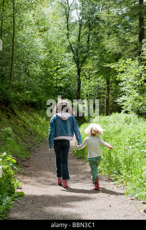 Día de verano - dos chicas caminando por un sendero forestal en la finca Dolaucothi National Trust Carmarthenshire Gales Occidental UK Foto de stock